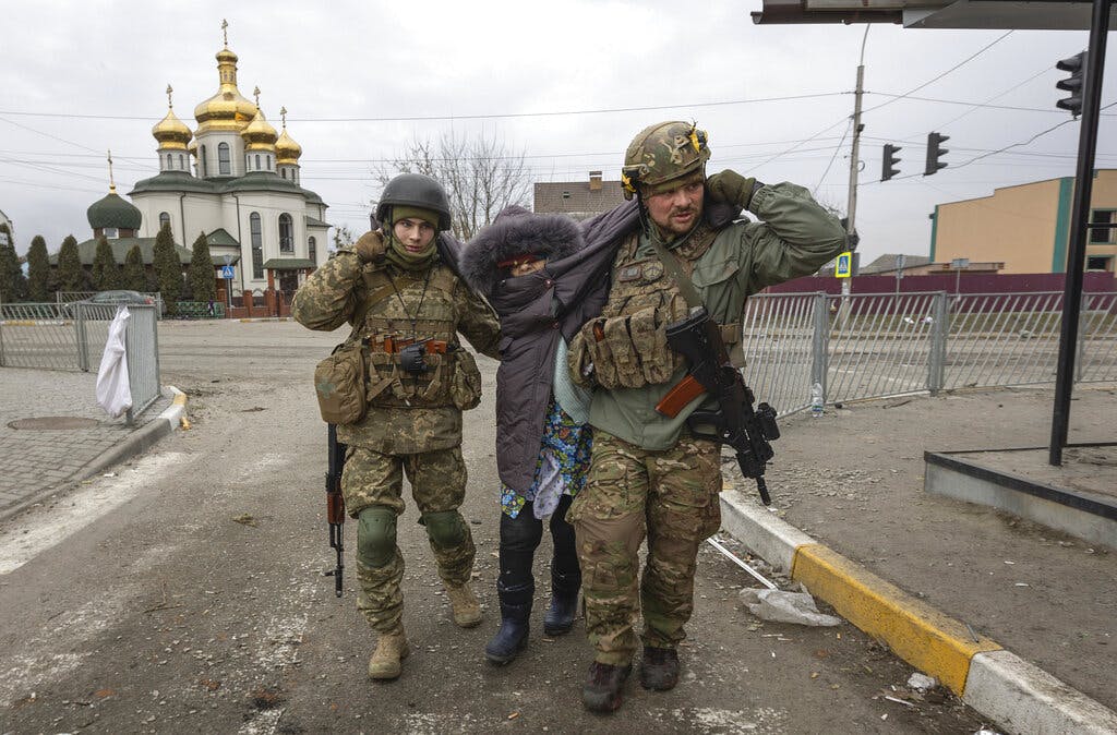 Ukrainian servicemen help an elderly woman at the town of Irpin, Ukraine, March 6, 2022. AP/Andriy Dubchak