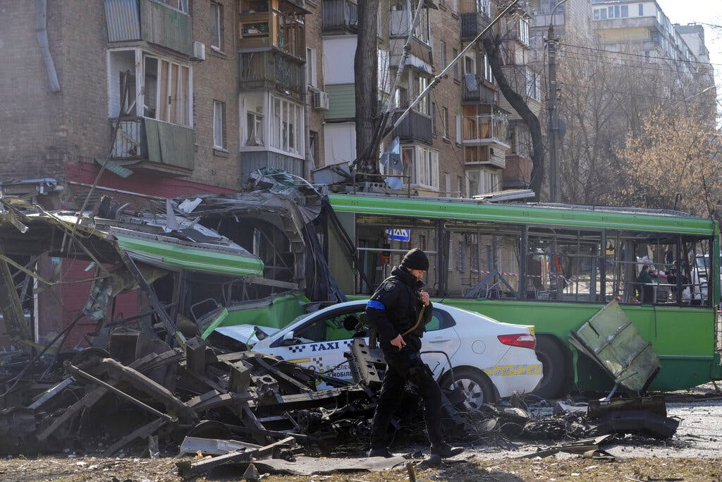 A Ukrainian soldier passes by a destroyed a trolleybus and taxi after a Russian bombing attack in Kiev March 14, 2022. AP/Efrem Lukatsky