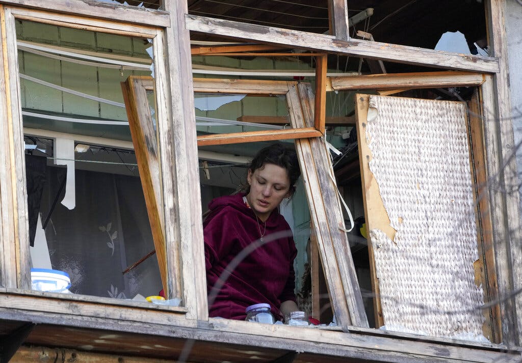A women stands near a broken window in her apartment after a Russian bombing attack in Kiev March 14, 2022. AP/Efrem Lukatsky
