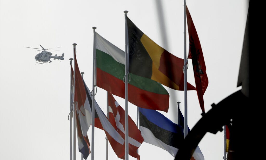 A police helicopter flies over NATO member country flags during a meeting of NATO defense ministers at NATO headquarters in Brussels, March 16, 2022. AP/Olivier Matthys