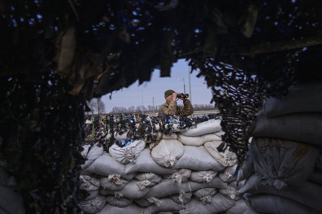 A Ukrainian soldier looks through binoculars at a military check point at Lityn, Ukraine, March 16, 2022. AP/Rodrigo Abd