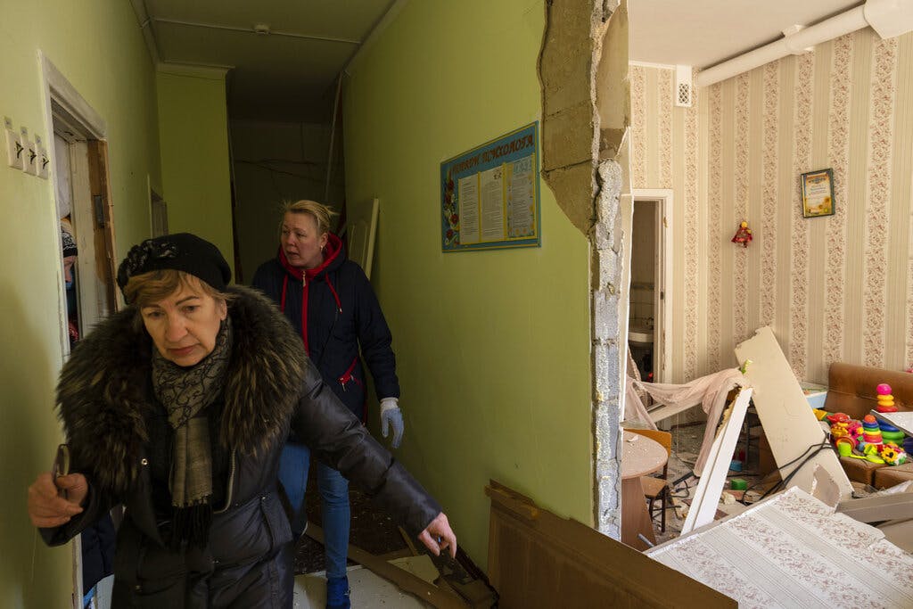 Women walks inside a Kiev school damaged with residential buildings during a bombing March 18, 2022. AP/Rodrigo Abd