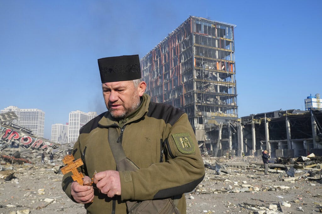 A priest prays by the ruins of a destroyed shopping center at Kyiv March 21, 2022. AP/Efrem Lukatsky