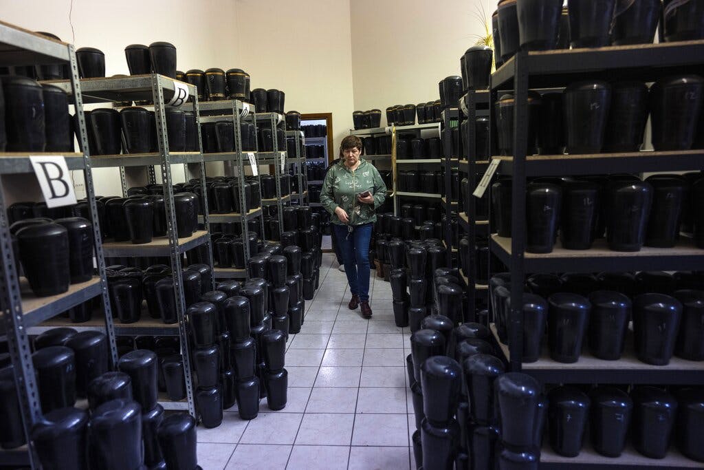 A cemetery worker walks amid marble urns  containing cremated remains inside Baikove's cemetery offices, Kiev, March 24, 2022.AP/Rodrigo Abd