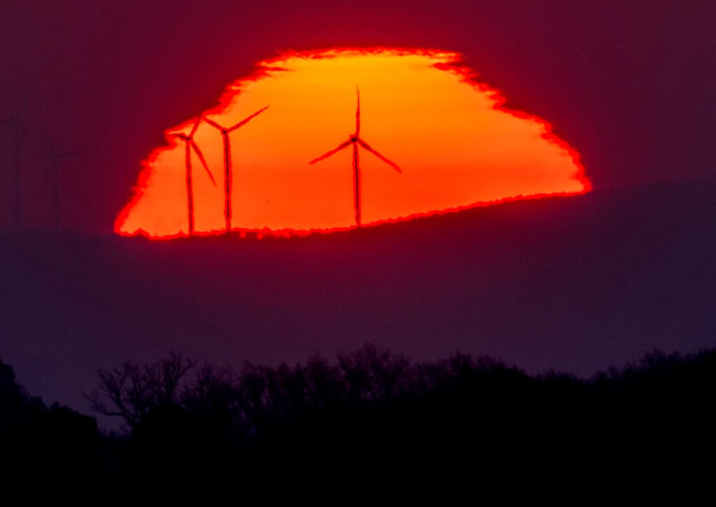 AP Photo/Michael Probst, file Wind turbines stand in front of the rising sun at Frankfurt, Germany on March 11.