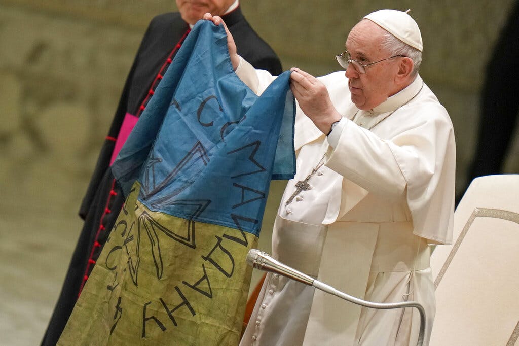 Pope Francis shows a flag that was brought to him from Bucha, Ukraine, at the Vatican April 6, 2022. AP/Alessandra Tarantino