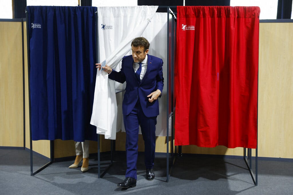 Presidentl Macron exits a voting booth April 24, 2022. Gonzalo Fuentes; pool via AP