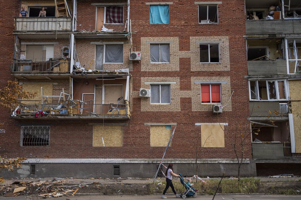 A woman pushes a baby stroller near a building damaged during a Russian attack in Slovyansk, eastern Ukraine, Saturday, June 4, 2022. (AP Photo/Bernat Armangue)