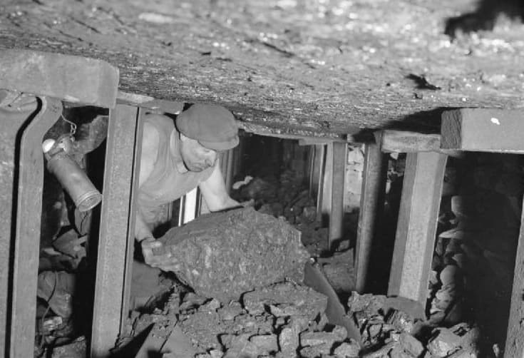 Via Wikimedia Commons A British coal miner lifts a large lump of coal onto the conveyor belt in 1944.