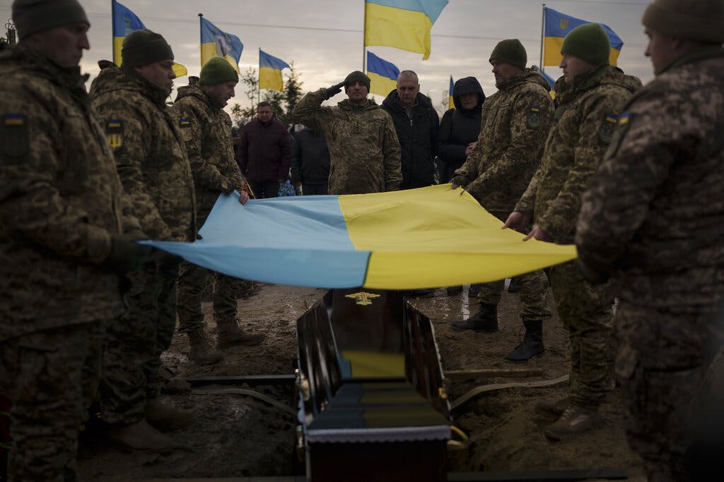 Tentara Ukraina mengibarkan bendera nasional mereka di atas peti mati Dmytro Kyrychenko saat pemakamannya di Bucha, Ukraina, 23 Desember 2022.  