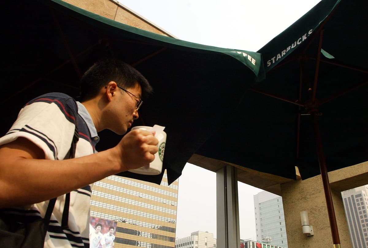 Chung Sung-Jun/Getty Images A customer drinks a beverage from Starbucks coffee store in Seoul, South Korea.