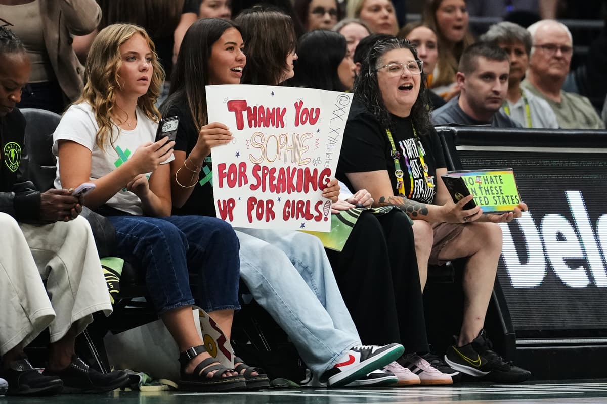 AP/Lindsey Wasson A fan holds a sign for Indiana Fever guard Sophie Cunningham for her comments on transgender athletes during the first half of a WNBA basketball game, July 28, 2026, at Seattle.