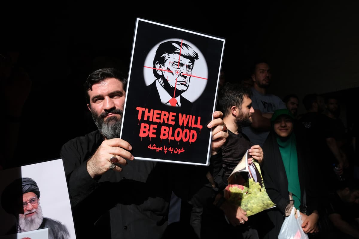 Kaveh Kazemi/Getty Images A man holds a mini poster with image of Donald Trump with a written message 'There will be blood' next to image of Ayatollah Khamenei and his son Mojtaba on July 5, 2026 at Tehran, Iran.