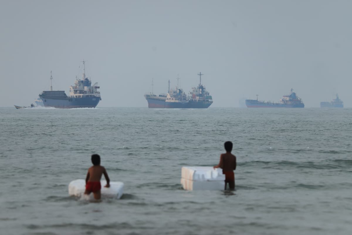 Amirhosein Khorgooi/ISNA via AP Two boys stand play with foam floats as cargo ships and other vessels are seen in the Strait of Hormuz off Bandar Abbas, Iran, on June 30, 2026.