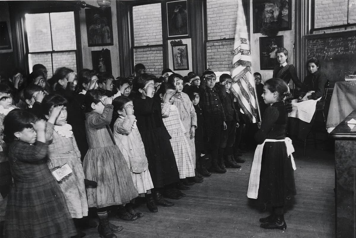 Via Wikimedia Commons Detail of Jacob Riis's photograph of students saluting the flat at the Mott Street Industrial School, New York City.