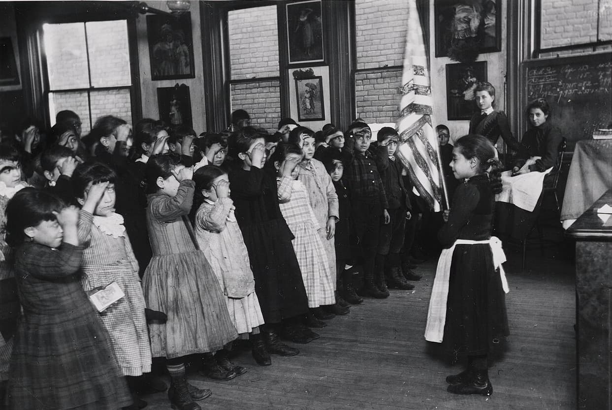 Via Wikimedia Commons Detail of Jacob Riis's photograph of students saluting the flat at the Mott Street Industrial School, New York City.