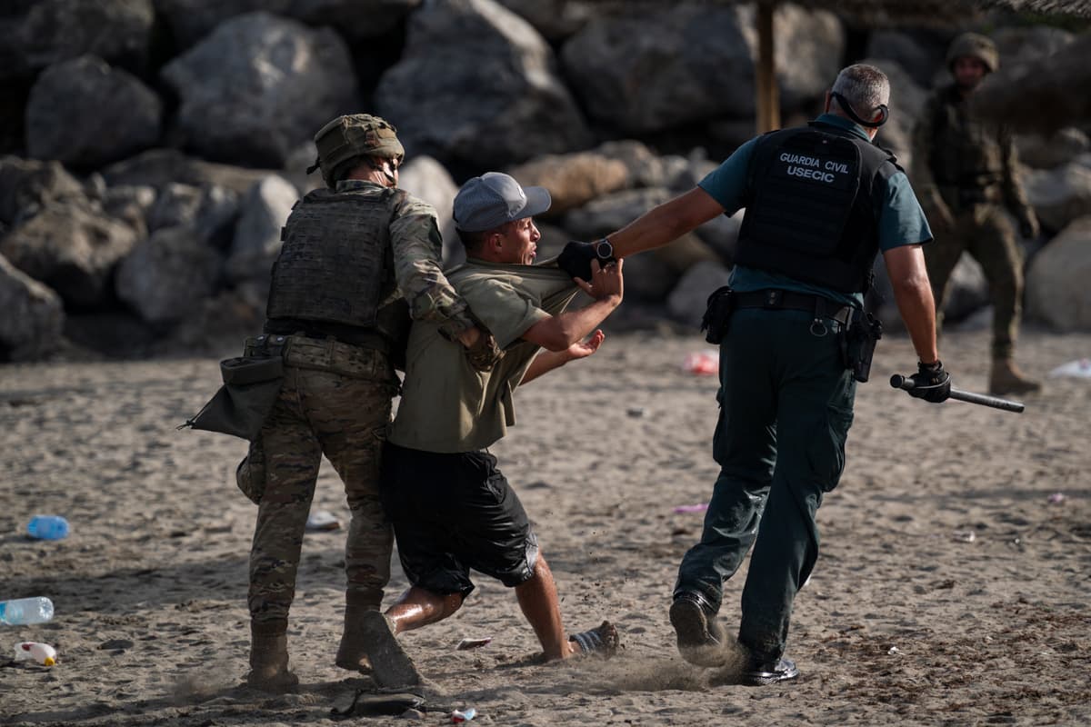 Adri Salido/Getty Images Security forces detain one of the thousands of would-be migrants who have flooded into the Spanish enclave of Ceuta on July 31, 2026.