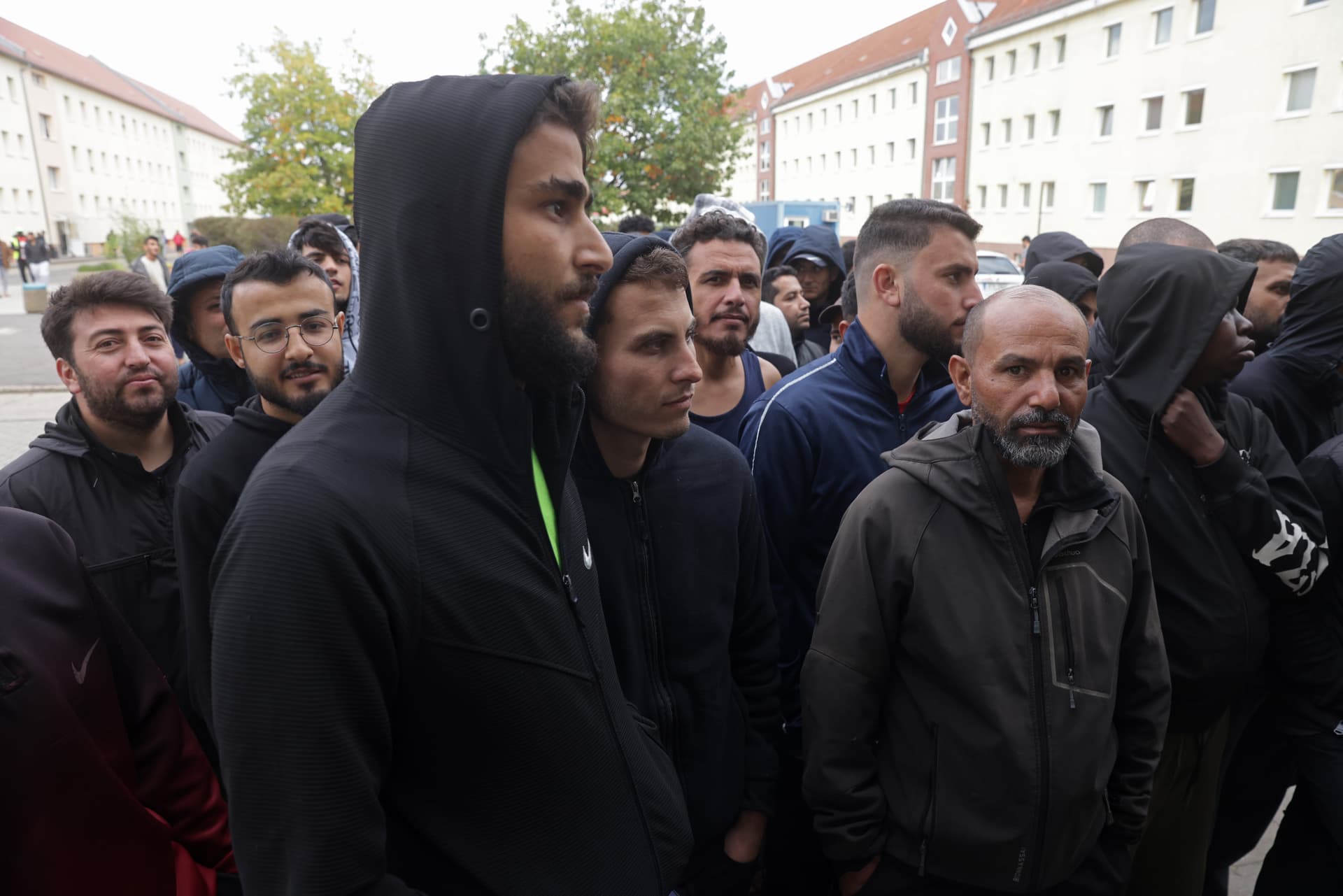 Sean Gallup/Getty Images Men, most of them from Syria, line up for lunch at a reception facility for migrants and refugees at Eisenhuettenstadt, Germany, on October 5, 2023.