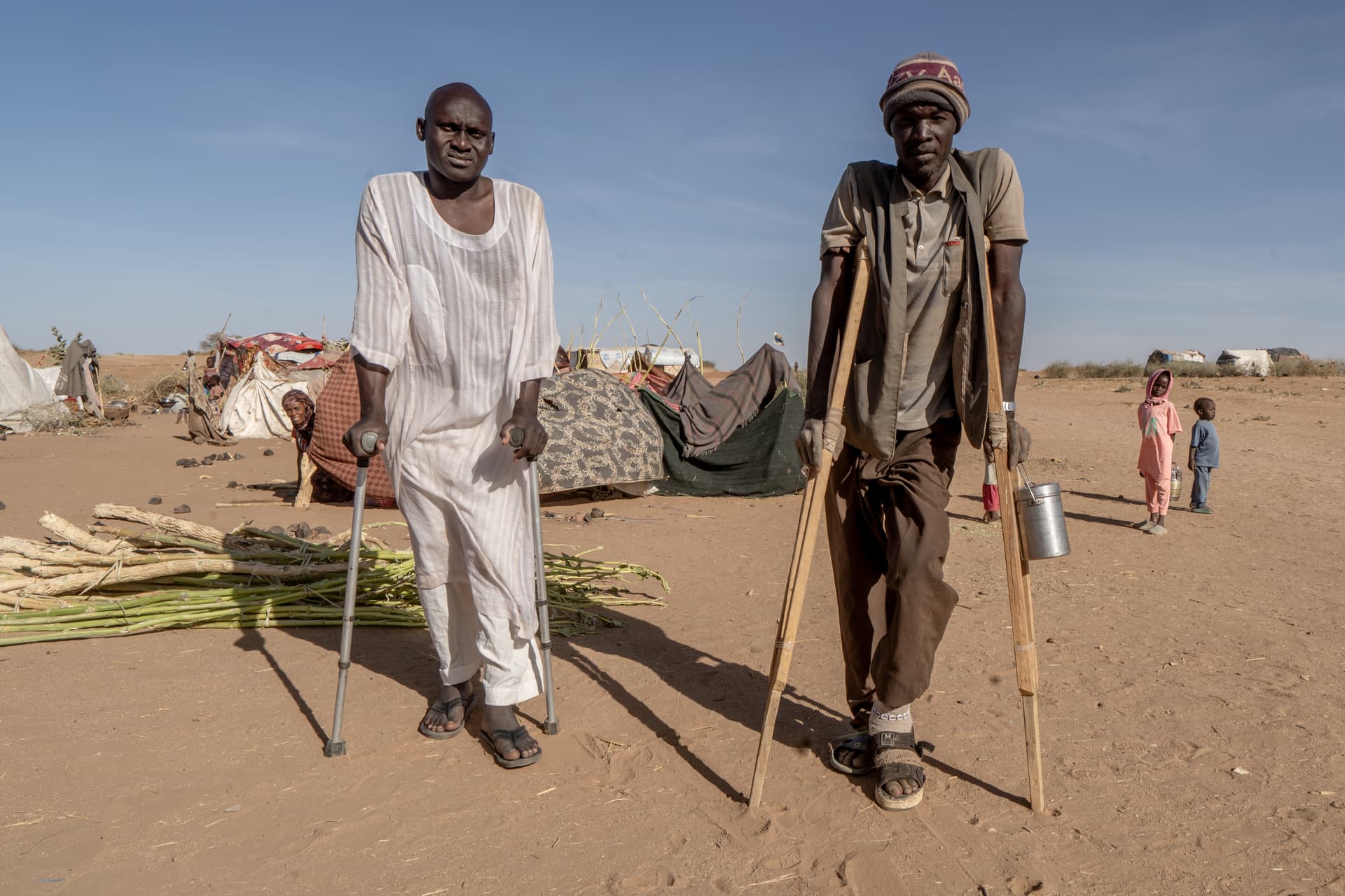 Giles Clarke/Avaaz via Getty Images Two wounded men stand at a food distribution site at a displaced persons camp near El Fashir in western Sudan’s Darfur region on February 28, 2026.